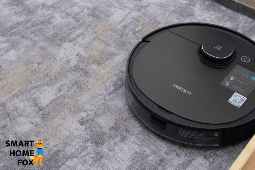 Der Deebot OZMO 950 beim Sand-Saugtest auf einem kurzen Teppich